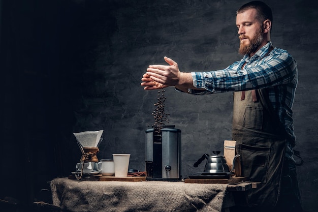 Portrait en studio d'un homme barbu rousse préparant un cappuccino dans une machine à café.