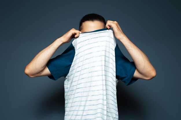 Portrait en studio d'un homme déshabillant la chemise sur fond bleu