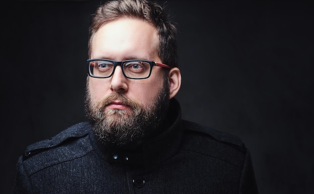 Portrait en studio d'un homme dodu sérieux dans des lunettes sur fond gris.