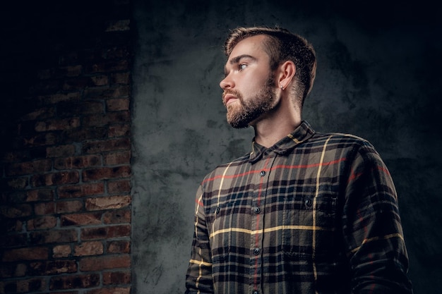 Portrait en studio d'un homme hipster barbu aux yeux bleus sur fond gris.