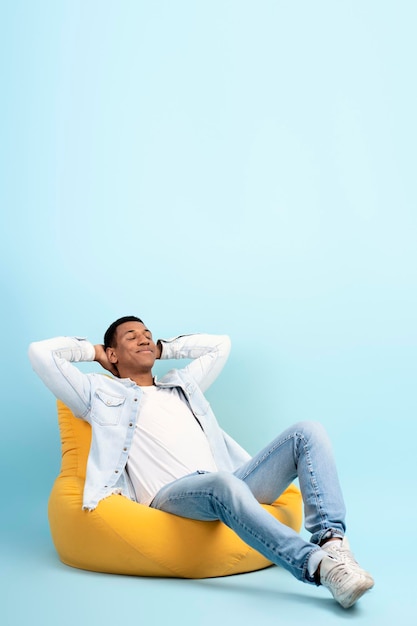 Portrait en studio d'un homme joyeux détendu fauteuil relaxant isolé sur mur bleu