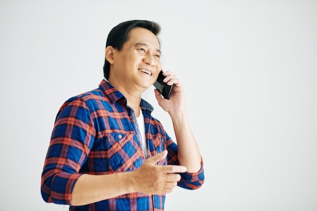 Portrait en studio d'un homme mûr souriant heureux parlant au téléphone avec un ami ou un parent