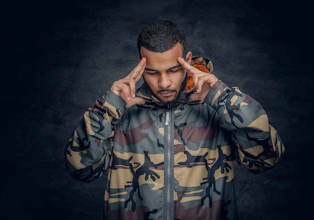 Portrait en studio d'un homme noir vêtu d'une veste militaire.