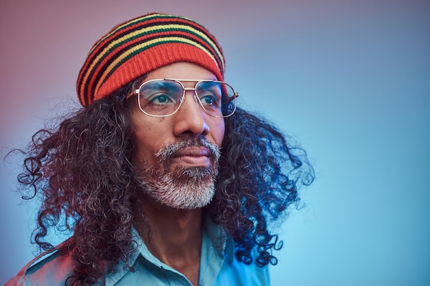 Portrait en studio d'un homme Rasta africain portant une chemise bleue et un bonnet. Isolé sur un fond bleu.