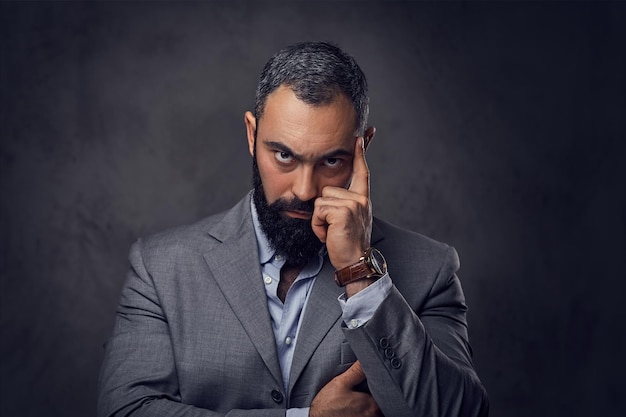 Portrait en studio d'un homme sérieux et barbu vêtu d'un costume.