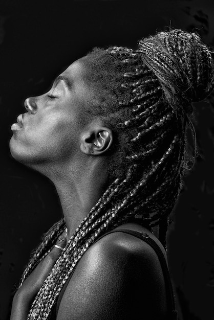 Portrait en studio d'une jeune femme noire avec des tresses et un fond noir