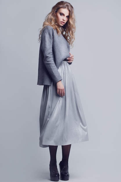 Portrait en studio d'une jeune fille élégante pleine longueur dans une jupe grise et un pull gris