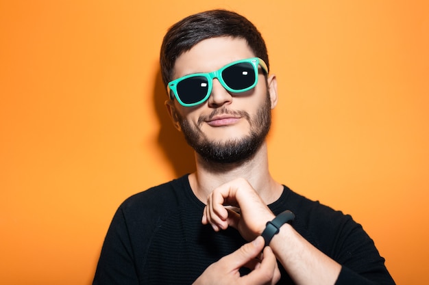 Portrait en studio de jeune homme confiant, lunettes de soleil