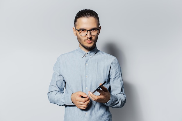 Portrait en studio de jeune homme avec smartphone dans les mains sur fond gris clair