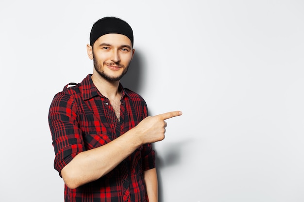 Portrait en studio de jeune homme souriant pointant le doigt sur fond blanc