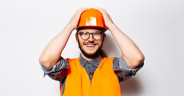 Portrait en studio d'un jeune ingénieur heureux dans un équipement orange sur fond blanc