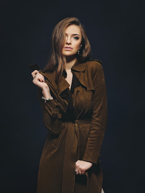 Portrait en studio d'un jeune mannequin portant un manteau avec un mur sombre en arrière-plan