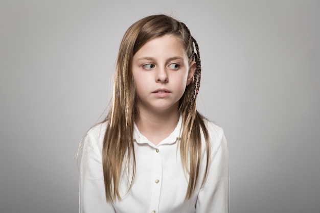 Portrait en studio d'une jolie fille aux longs cheveux blonds regardant de travers sur fond neutre