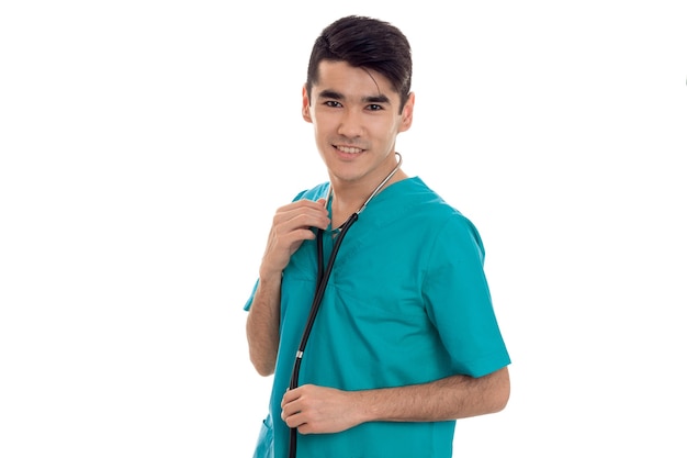 Portrait en studio de joyeux médecin de sexe masculin en uniforme posant isolé sur mur blanc