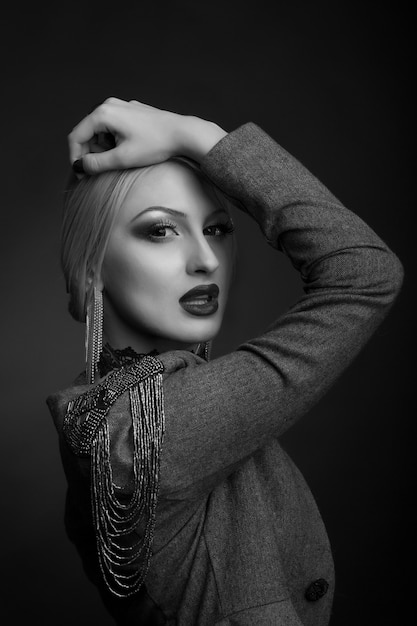 Portrait de studio noir et blanc élégant d'une femme séduisante avec un maquillage lumineux porte une veste sur un corps nu