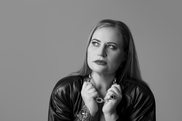 Portrait en studio vertical de belle femme posant isolé sur fond gris. Photographie noir et blanc