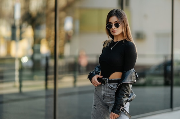 Portrait de style de jeune fille à la mode marchant le long de la rue