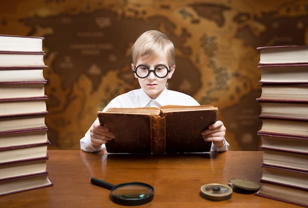 Portrait de style rétro d'un garçon de lecture contre une vieille carte du monde