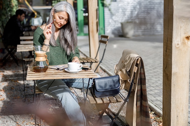 Portrait de style de vie femme élégante cheveux pâles matures à l'extérieur près du café