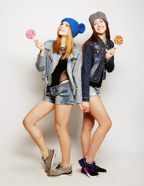 Portrait de style de vie de mode en gros plan de deux jeunes filles hipster meilleures amies tenant des bonbons faisant des grimaces et s'amusant