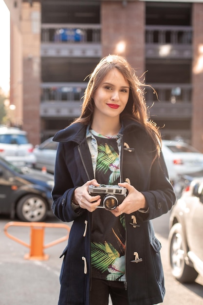 Portrait de style de vie souriant d'automne en plein air d'une jolie jeune femme, s'amusant dans la ville avec un appareil photo, photo de voyage du photographe. Faire des photos dans un style hipster.