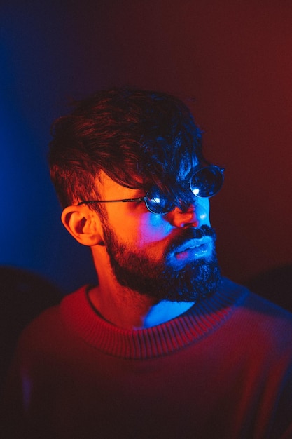 Portrait stylisé d'un homme avec une barbe et des lunettes modernes noires utilisant 2 sources de lumière colorée