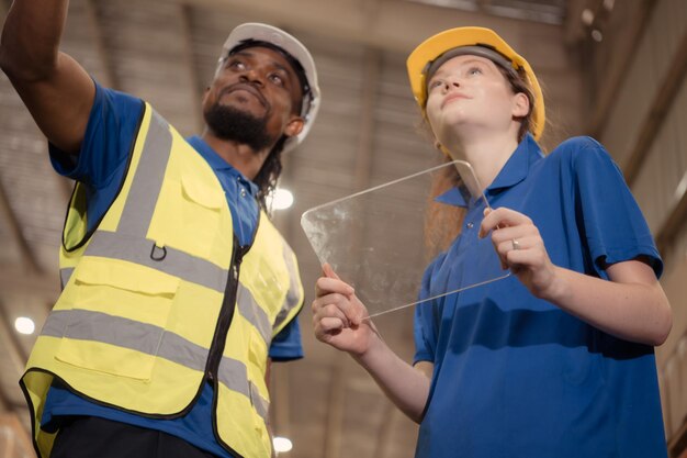 Photo portrait d'un superviseur masculin confiant et d'une employée travaillant ensemble dans un entrepôt avec une tablette.