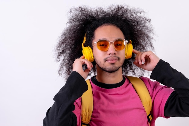 Portrait avec t-shirt rose et sac à dos écoutant de la musique en streaming Jeune homme aux cheveux afro sur fond blanc