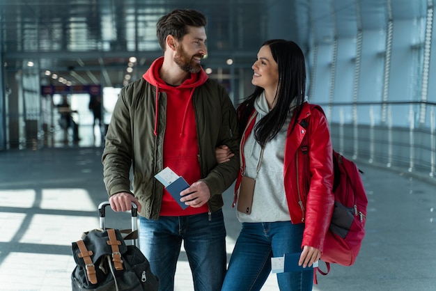 Portrait à la taille du couple de voyageurs se sentant heureux tout en se tenant dans le hall de l'aéroport et attend avec impatience son voyage. Banque d'images