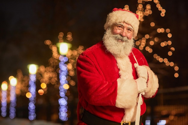 Portrait à la taille du père noël traditionnel tenant un sac avec des cadeaux et souriant à la caméra en nig