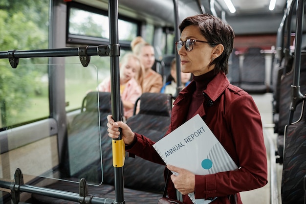 Portrait de taille d'une femme adulte élégante tenant une balustrade dans un bus lors d'un voyage en transport en commun...