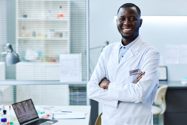 Portrait à la taille d'un homme noir souriant debout dans un espace de copie de laboratoire médical