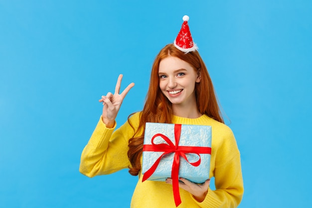 Portrait de taille de jolie femme rousse heureuse recevoir un cadeau dans une boîte enveloppée, célébrant Noël