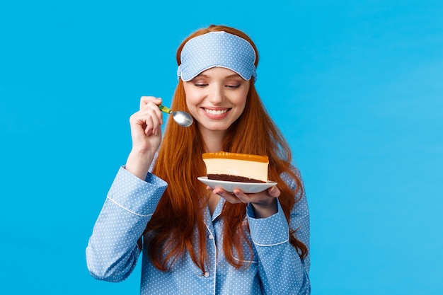 Portrait de taille joyeuse et ravie jeune femme rousse caucasienne en pyjama et masque de sommeil