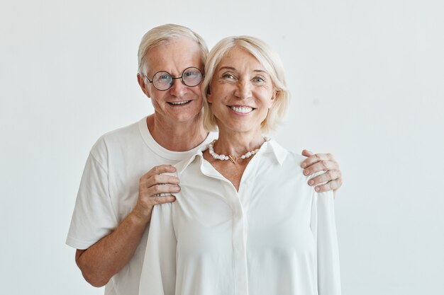 Portrait de taille minimale d'un couple de personnes âgées moderne embrassant sur fond blanc et regardant ...