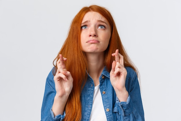 Portrait de taille plein d'espoir et nerveuse jolie fille sombre aux cheveux rouges, yeux bleus