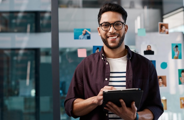 Portrait technologique d'un homme d'affaires heureux avec une tablette et debout au bureau au travail Médias sociaux ou réseautage Jeune homme d'entreprise et créatif avec un appareil mobile vérifiant ses e-mails sur le lieu de travail