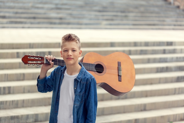 Photo portrait teenager boy avec guitare acoustique dans le parc.