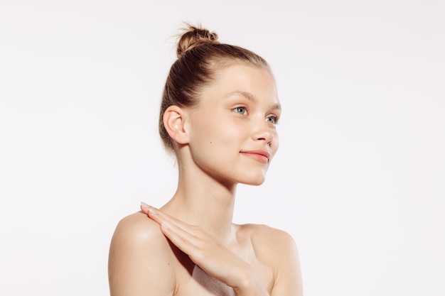 Portrait d'une tendre belle jeune fille avec un maquillage nude posant isolé sur fond de studio blanc Beauté naturelle