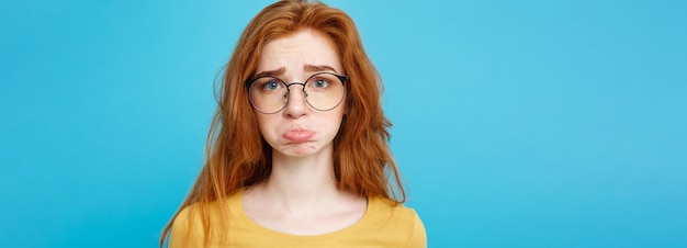 Portrait de tête de fille heureuse aux cheveux roux gingembre avec des taches de rousseur souriant regardant la caméra bleu pastel