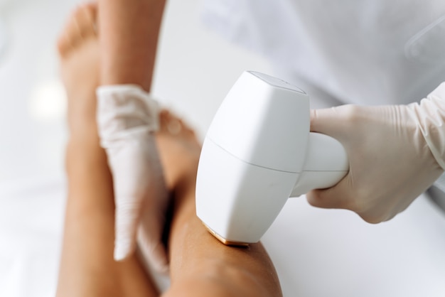 Portrait de tête recadrée d'une jeune femme mince et détendue ayant une procédure d'épilation des jambes dans la zone du genou. Stock photo