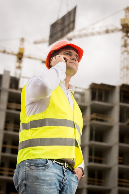 Portrait tonique d'un jeune ingénieur en construction parlant par téléphone sur un chantier de construction.