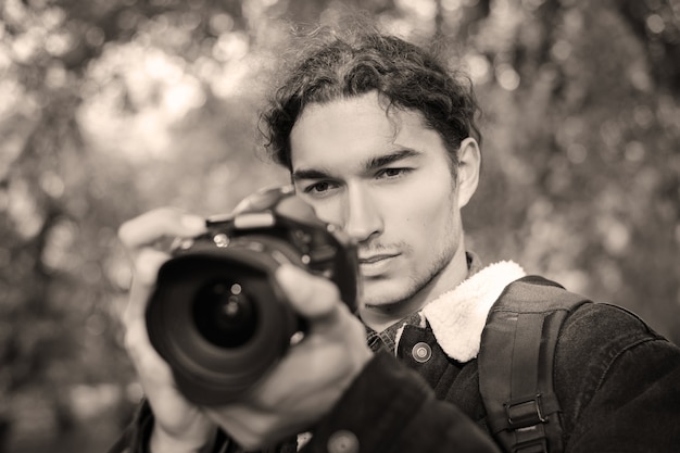 Portrait tonique d'un photographe avec appareil photo pendant la prise de vue en extérieur
