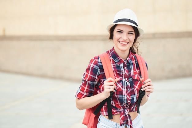 Portrait d'une touriste joyeuse avec chapeau en ville