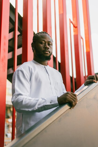 Portrait de touriste masculin joyeux vêtu de blanc portant dashiki ethnique souriant dans une rue de la ville ou un petit