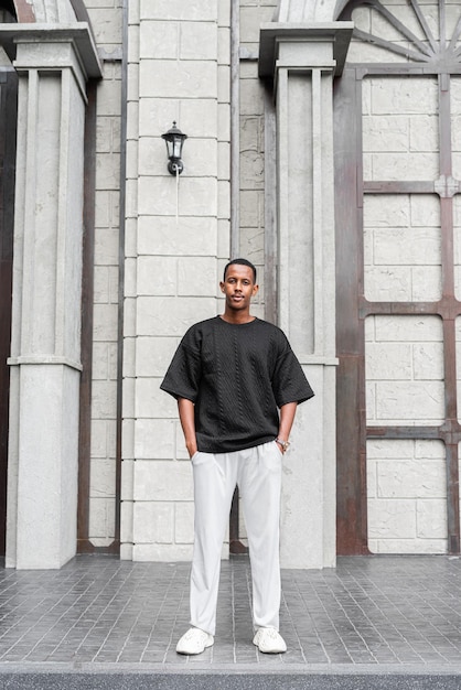 Portrait de toute la longueur du beau jeune homme africain debout à l'extérieur