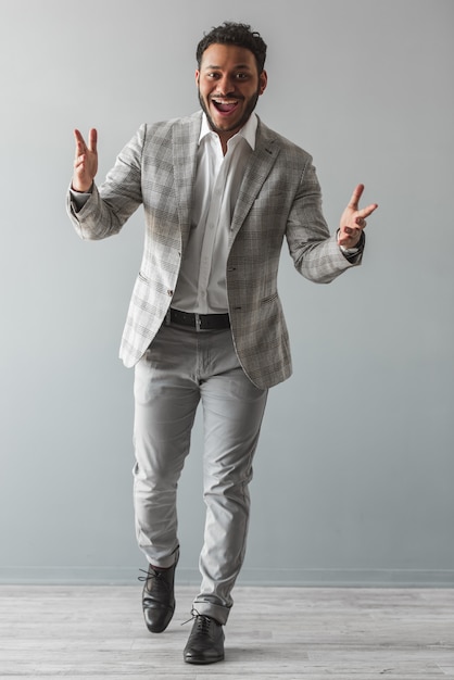 Portrait de toute la longueur de l'élégant mec afro en costume gris.