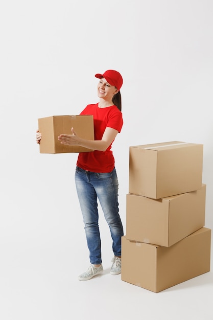 Portrait de toute la longueur d'une femme de livraison en casquette rouge, t-shirt donnant des boîtes de commande isolées sur fond blanc. Courrier féminin près de boîtes en carton vides. Réception du colis. Copiez l'espace pour la publicité.