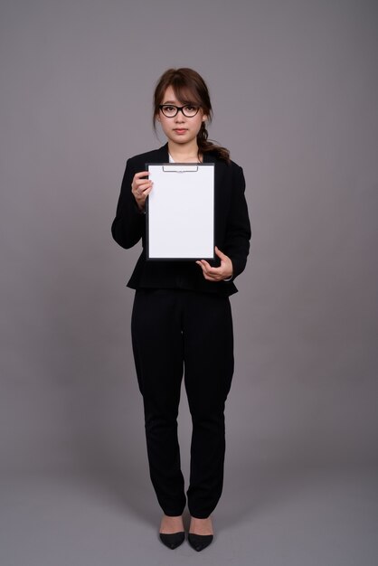 Portrait de toute la longueur de la jeune femme d'affaires asiatique debout