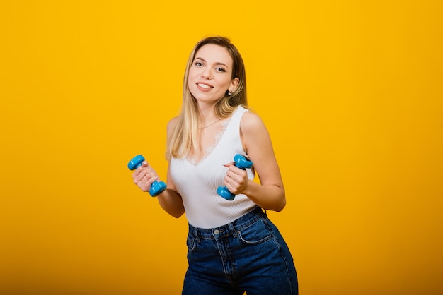 Portrait de toute la longueur de la jeune fille de remise en forme souriante en forme parfaite, tourné en studio, fond jaune